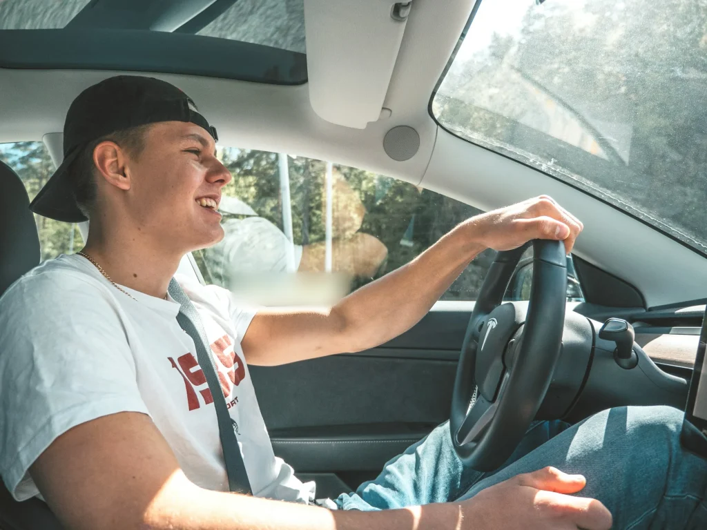 Smiling teen driver with both hands on the steering wheel