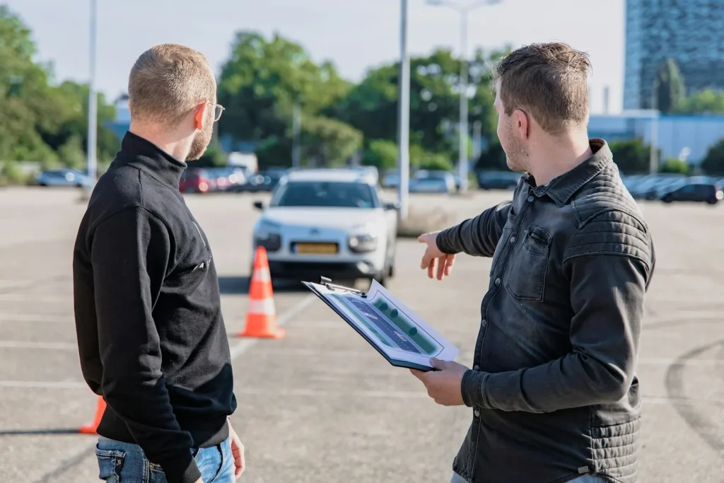 Driving instructor with a clipboard explaining a road test course to a student
