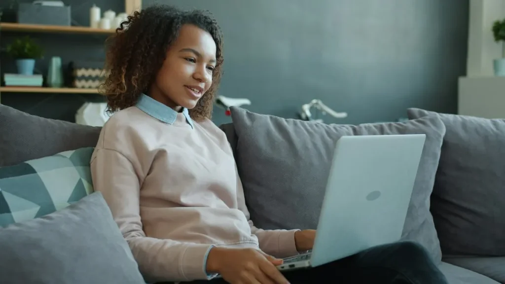 Teen relaxing on a couch while working through a course on a laptop