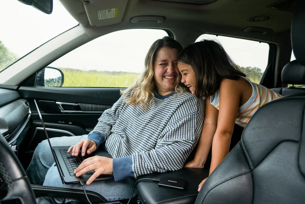 Parent and teen laughing together in the front seat of a car