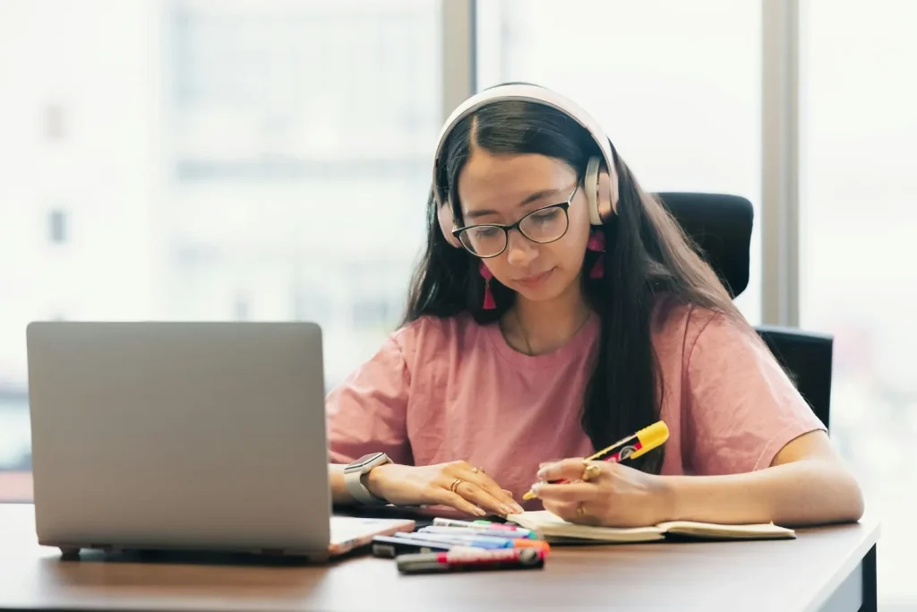 Teen student with headphones taking an online course on a laptop