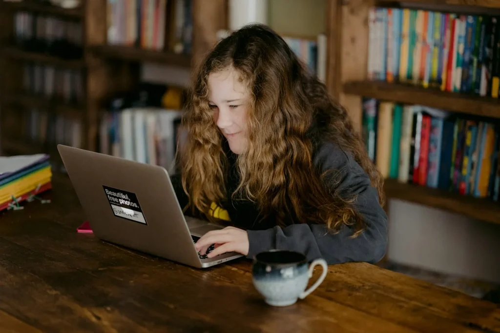 Student studying on a laptop at a wooden table