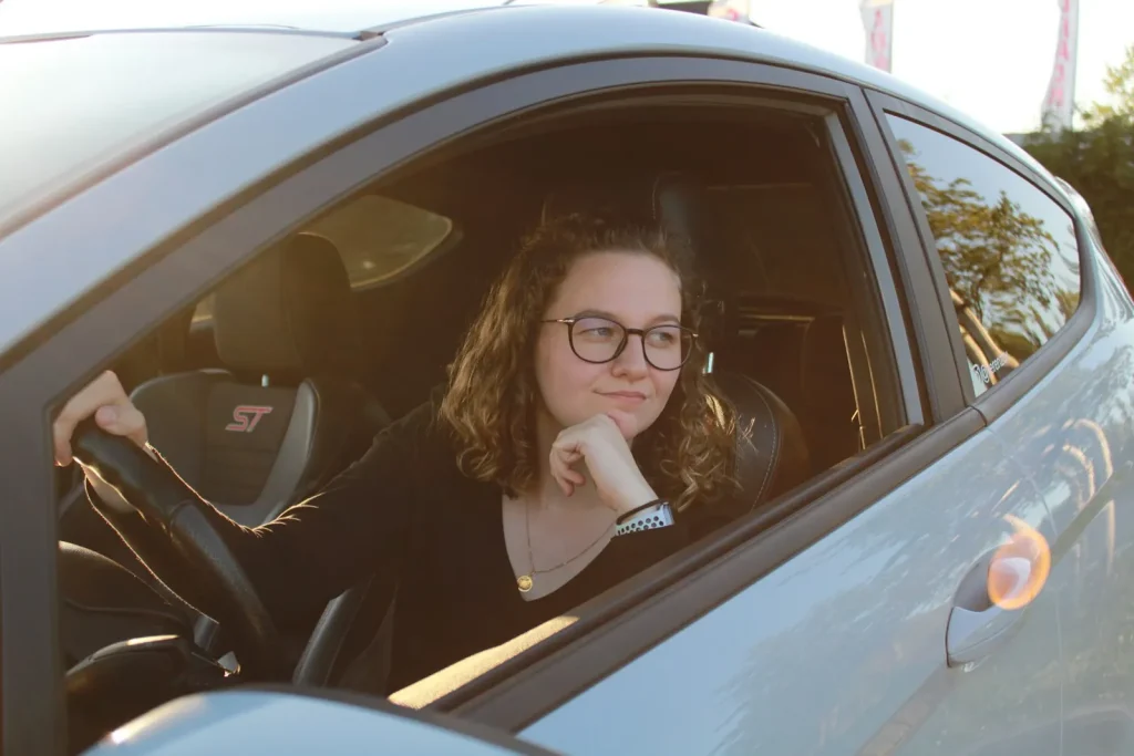 Young driver in glasses sitting behind the wheel of a car